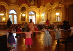 Dzieci tańczą w balowych strojach w Sali Balowej w Pałacu I. Poznańskiego.